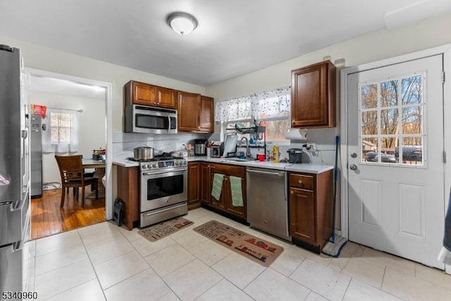 kitchen with light tile patterned floors, light countertops, decorative backsplash, appliances with stainless steel finishes, and a sink