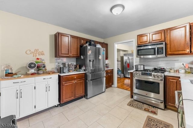 kitchen featuring light tile patterned flooring, stainless steel appliances, light countertops, backsplash, and brown cabinetry