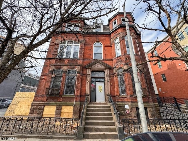 victorian house with a fenced front yard and brick siding