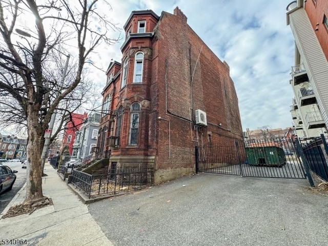 view of side of property featuring brick siding, fence, and a gate