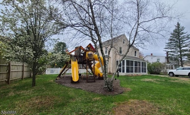 view of play area with a sunroom, fence, and a yard