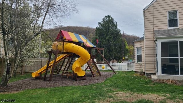 view of jungle gym with fence and a lawn