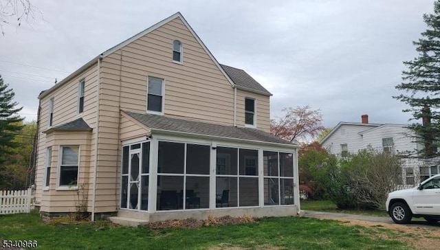back of house featuring a sunroom, a lawn, and fence