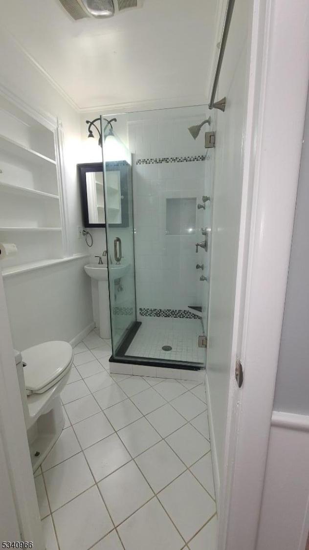 bathroom with tile patterned flooring, toilet, and a shower stall