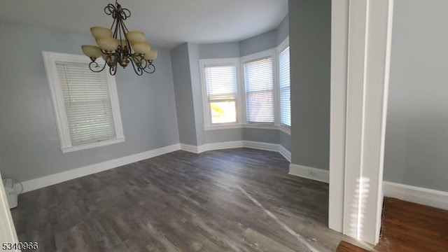 unfurnished dining area featuring baseboards, a chandelier, and dark wood finished floors