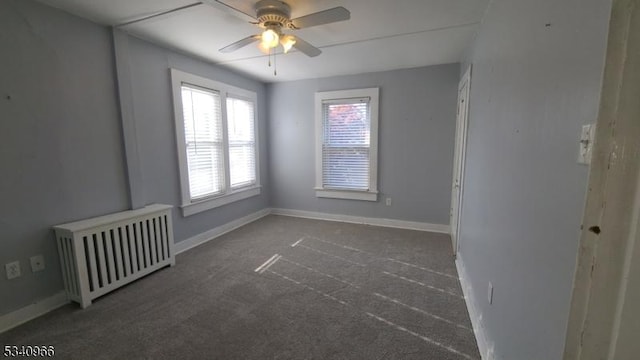 spare room with baseboards, carpet flooring, radiator, and ceiling fan