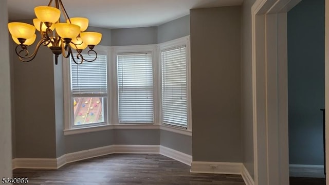 unfurnished dining area with baseboards, dark wood-style floors, and a notable chandelier