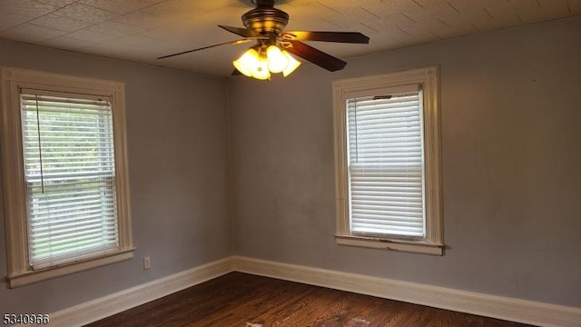 spare room with baseboards, a ceiling fan, and dark wood-type flooring