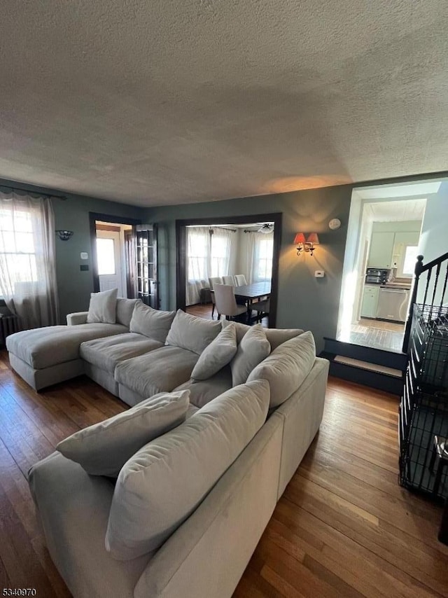 living room with a healthy amount of sunlight, stairway, a textured ceiling, and wood finished floors