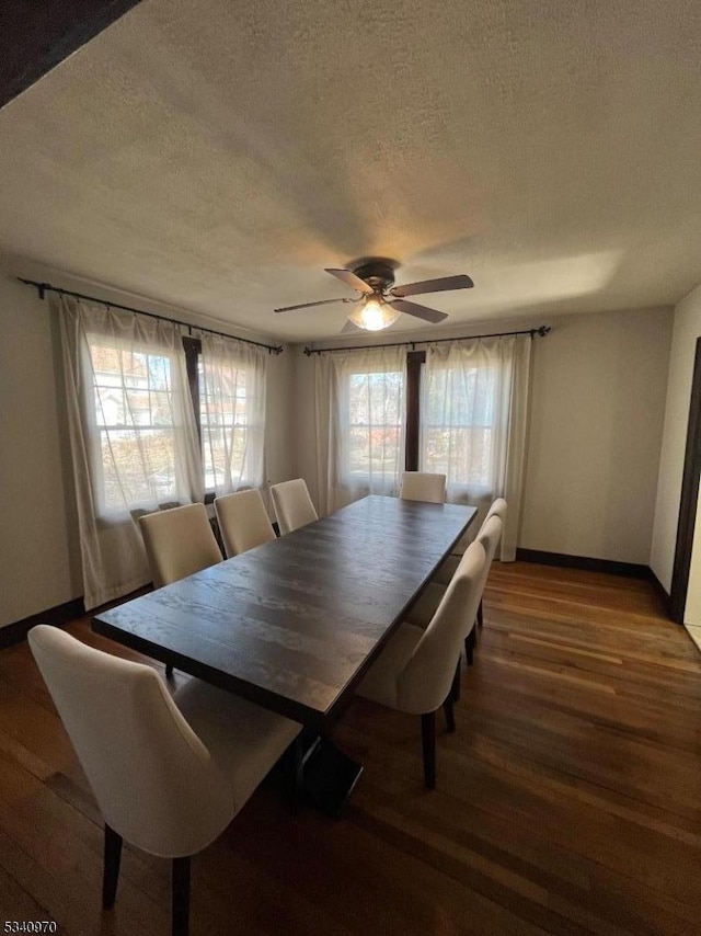 dining space featuring a ceiling fan, a textured ceiling, baseboards, and wood finished floors