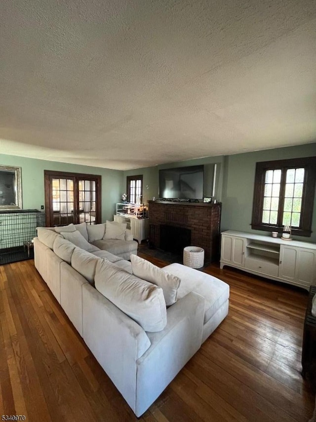 living room with dark wood-type flooring, a fireplace, and a healthy amount of sunlight