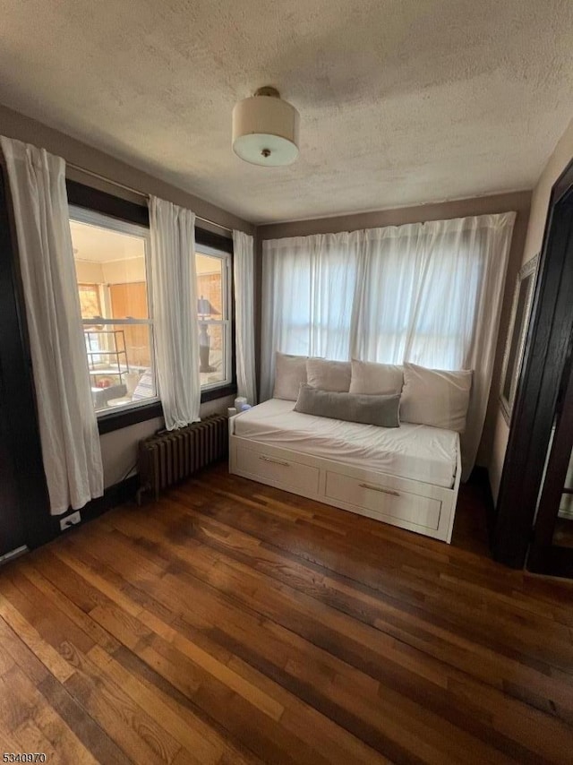 unfurnished room featuring radiator, a textured ceiling, and wood finished floors