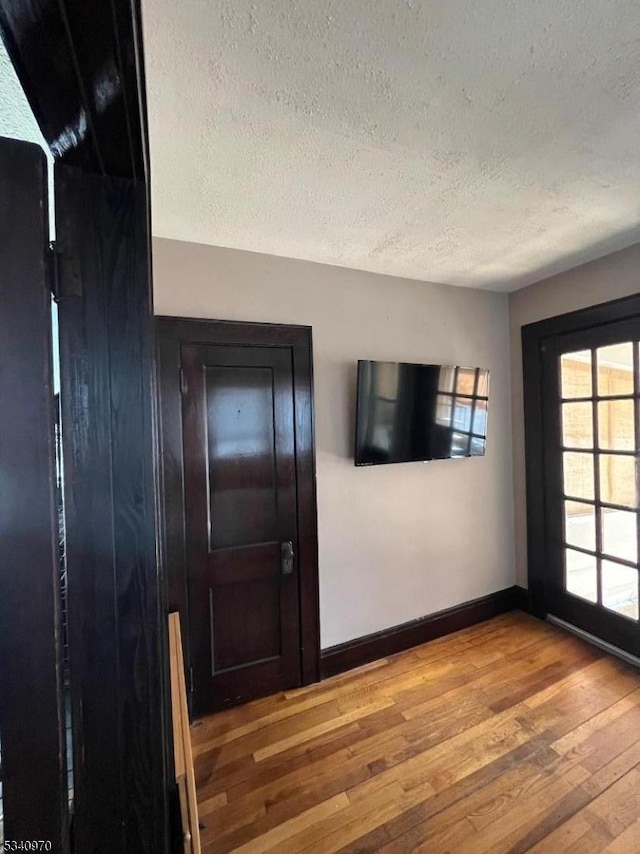 unfurnished room featuring a textured ceiling, baseboards, and hardwood / wood-style flooring