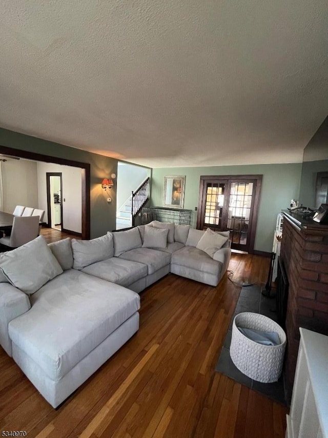 living room featuring stairs, a textured ceiling, and wood finished floors