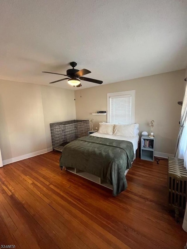 bedroom with hardwood / wood-style flooring, a ceiling fan, baseboards, and a textured ceiling