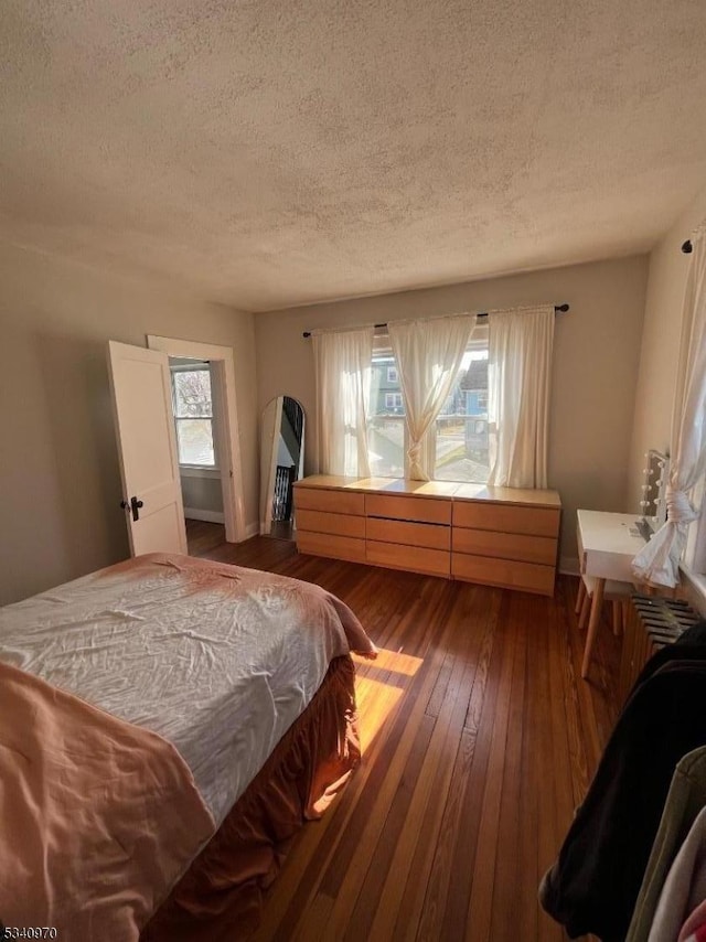 bedroom featuring wood-type flooring, arched walkways, and a textured ceiling