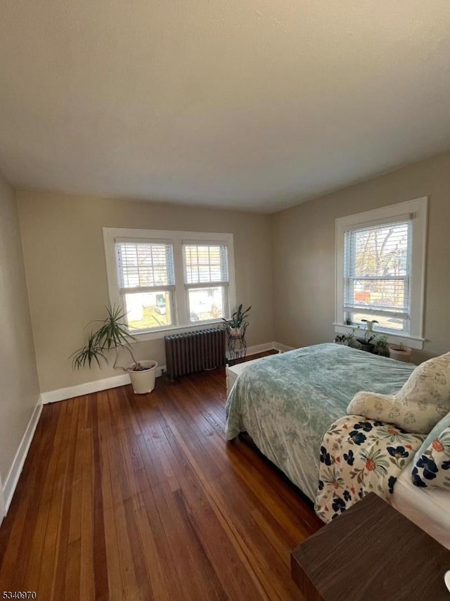 bedroom featuring radiator, multiple windows, baseboards, and dark wood-style flooring