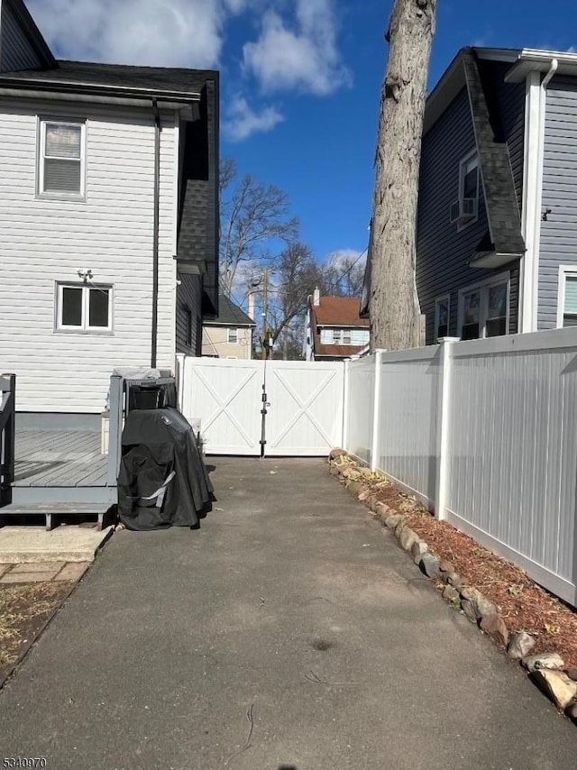 view of home's exterior with a fenced backyard, a gate, a deck, and a patio