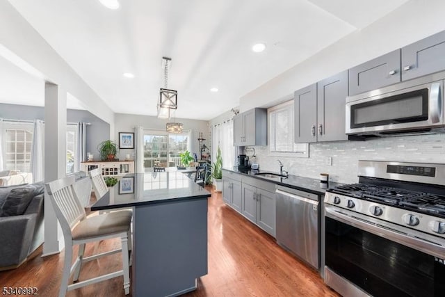 kitchen with decorative backsplash, a center island, stainless steel appliances, gray cabinetry, and a sink