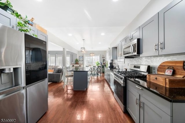 kitchen with stainless steel appliances, tasteful backsplash, dark wood finished floors, and gray cabinetry