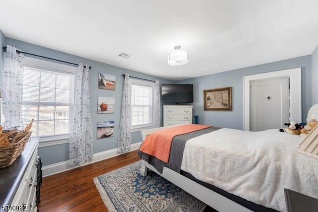 bedroom with visible vents, baseboards, and wood finished floors