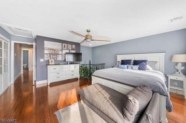 bedroom with dark wood-style floors, ceiling fan, visible vents, and baseboards