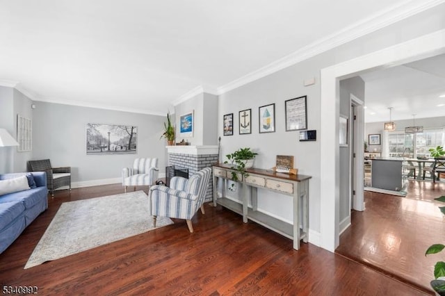 living area with crown molding, a fireplace, baseboards, and wood finished floors