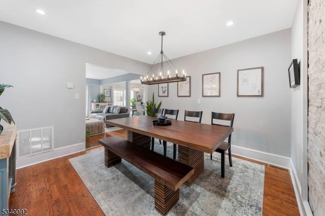 dining area with an inviting chandelier, baseboards, visible vents, and wood finished floors