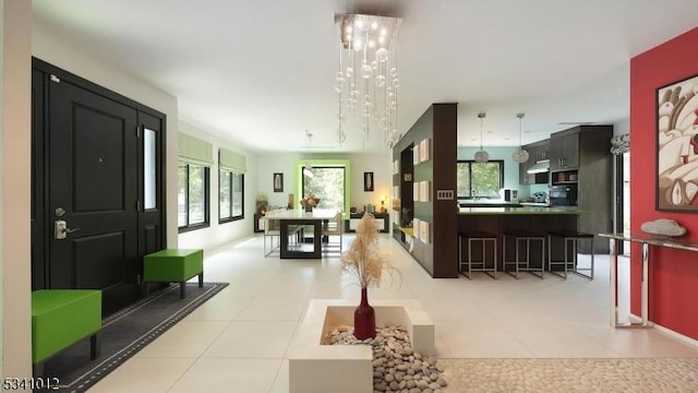 foyer entrance featuring light tile patterned floors, a notable chandelier, and a wealth of natural light