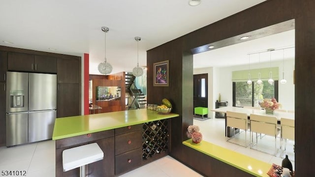 kitchen featuring light countertops, dark brown cabinetry, decorative light fixtures, and stainless steel fridge with ice dispenser