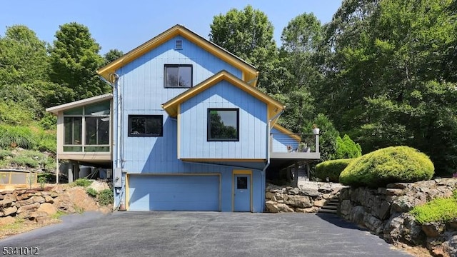 view of front facade featuring a garage, aphalt driveway, and a sunroom