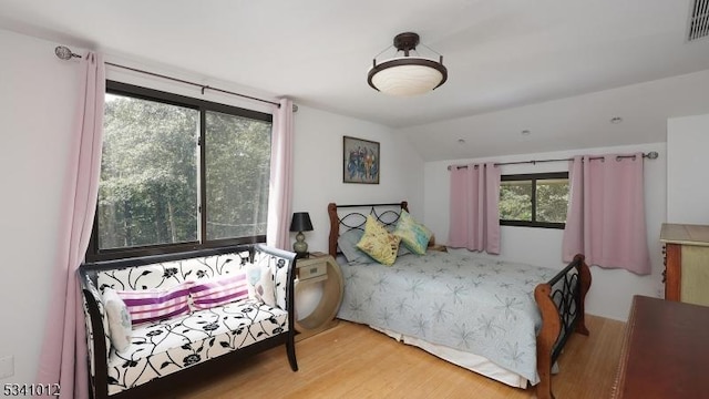 bedroom with lofted ceiling, visible vents, and wood finished floors