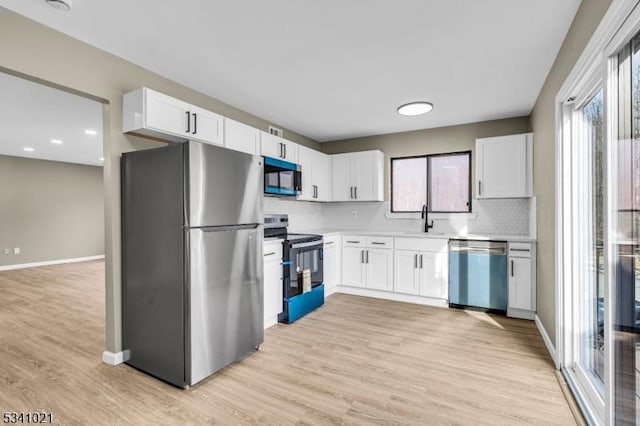 kitchen featuring appliances with stainless steel finishes, a sink, light countertops, light wood-type flooring, and backsplash