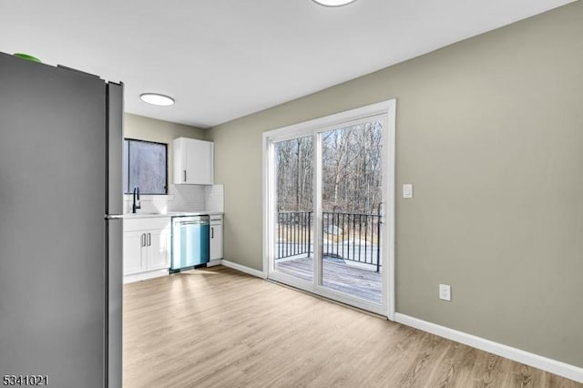 kitchen featuring tasteful backsplash, baseboards, light wood-style flooring, stainless steel appliances, and white cabinetry