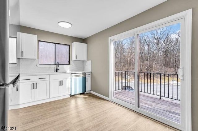 kitchen featuring stainless steel appliances, light countertops, a sink, and white cabinetry