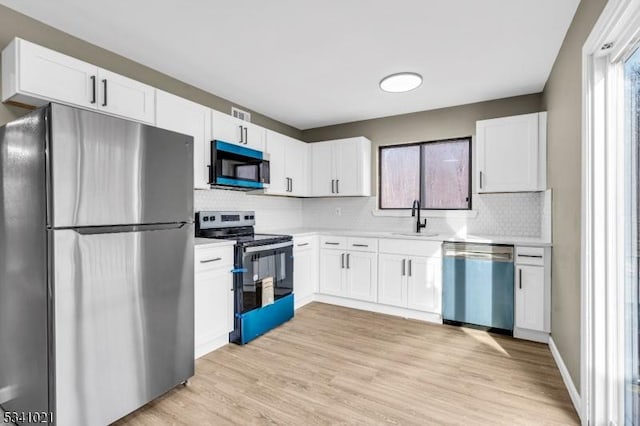 kitchen featuring appliances with stainless steel finishes, light countertops, a sink, and white cabinetry