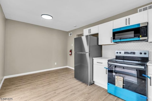 kitchen with light wood-style flooring, stainless steel appliances, visible vents, white cabinetry, and decorative backsplash