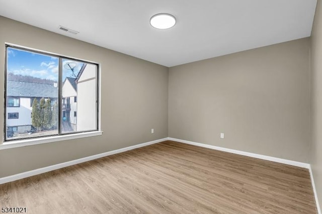 spare room with light wood-style flooring, visible vents, and baseboards