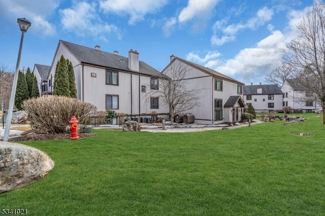 rear view of property featuring a lawn and a chimney