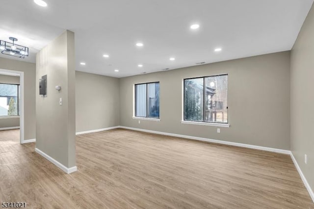 spare room featuring light wood finished floors, baseboards, and recessed lighting