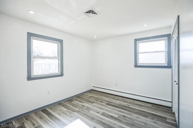 empty room with wood finished floors, visible vents, baseboards, a baseboard radiator, and recessed lighting