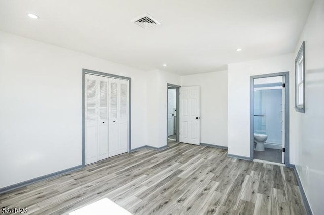 unfurnished bedroom with a closet, visible vents, light wood-style flooring, and baseboards