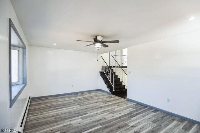 unfurnished room with wood finished floors, recessed lighting, stairway, baseboards, and baseboard heating