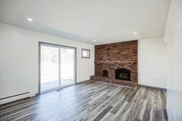 unfurnished living room featuring wood finished floors, a fireplace, baseboards, and baseboard heating