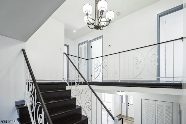 stairs with wood finished floors and a chandelier