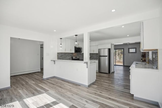 kitchen with a baseboard radiator, a peninsula, a sink, stainless steel appliances, and white cabinetry