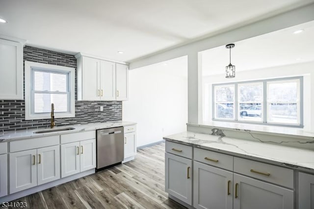 kitchen featuring a sink, light stone counters, backsplash, light wood-style floors, and dishwasher