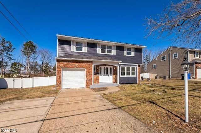 view of front of home with a front yard, fence, driveway, an attached garage, and brick siding