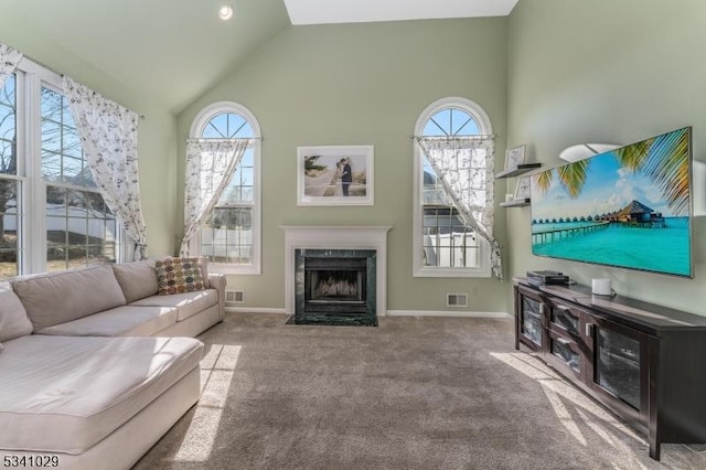 carpeted living room featuring plenty of natural light, visible vents, vaulted ceiling, and a high end fireplace