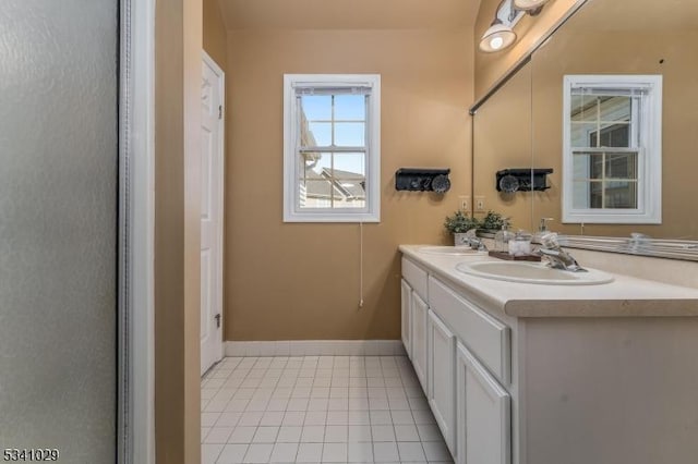 bathroom with double vanity, a sink, baseboards, and tile patterned floors